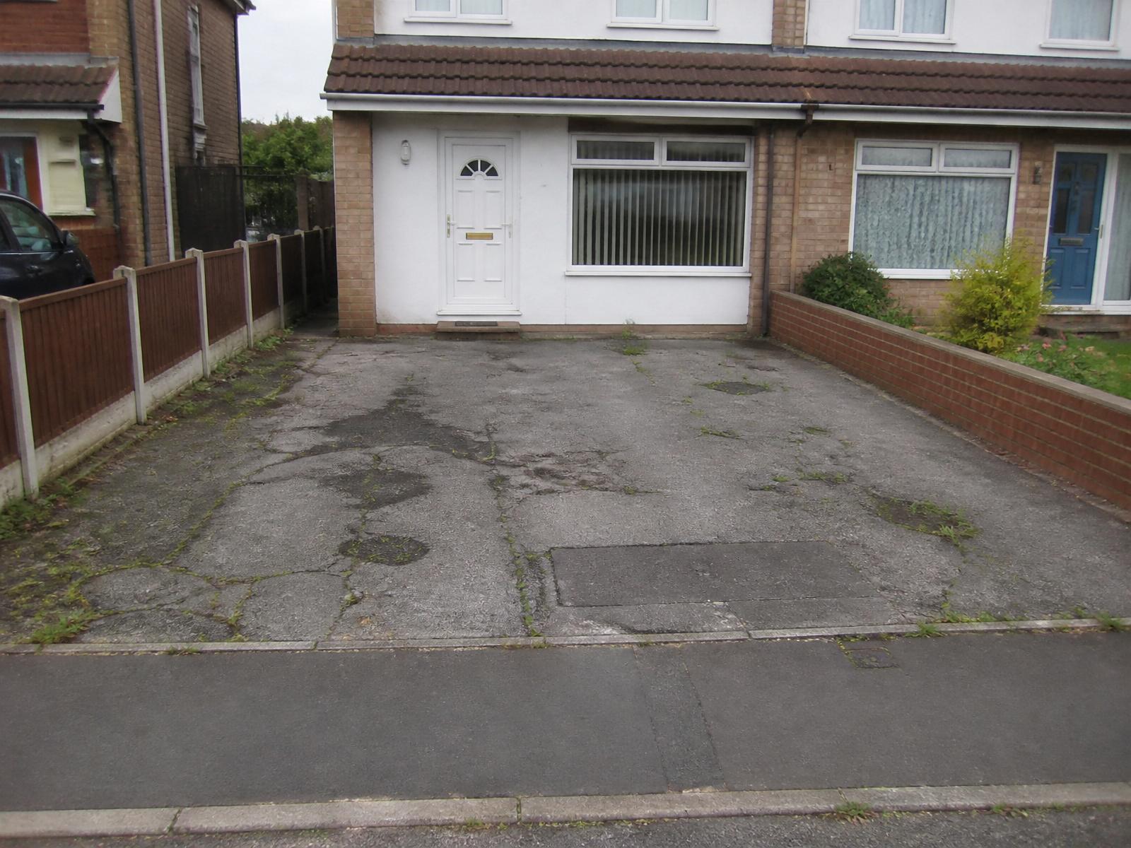 Tired cracked tarmac suburban driveway with weeds and oil stains before resin installation
